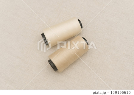 Two Beige Thread Spools on a Textured Surface Two Beige Thread Spools on a Textured Surface 139196610