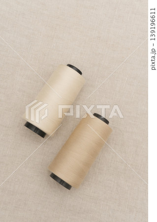 Two Beige Thread Spools on a Textured Surface Two Beige Thread Spools on a Textured Surface 139196611