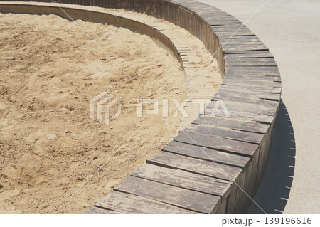 A sand pit with a curved wooden border in a sunny park A sand pit with a curved wooden border in a sunny park 139196616