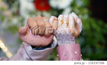 The bride and groom interlock their little fingers. 139197396