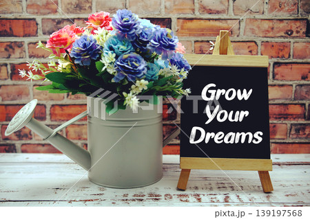 Grow Your Dreams text on black wooden easel and vase with flowers bouquet on brick wall background Grow Your Dreams text on black wooden easel and vase with flowers bouquet on brick wall background 139197568