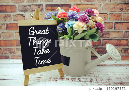 Great Things Take Time text on black wooden easel and vase with flowers bouquet on brick wall background Great Things Take Time text on black wooden easel and vase with flowers bouquet on brick wall background 139197571