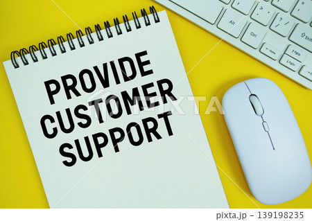 Notepad with the text "Provide Customer Support" and white keyboard and wireless mouse on yellow background 139198235