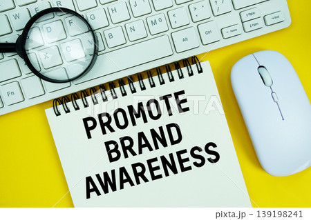 Notepad with the text "Promote Brand Awareness" and white keyboard, wireless mouse and magnifying glass on yellow background Notepad with the text "Promote Brand Awareness" and white keyboard, wireless mouse and magnifying glass on yellow background 139198241