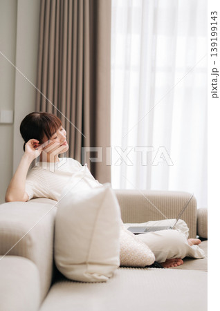 Beautiful peaceful asian woman resting on comfortable living room sofa after remote business work and home study 139199143