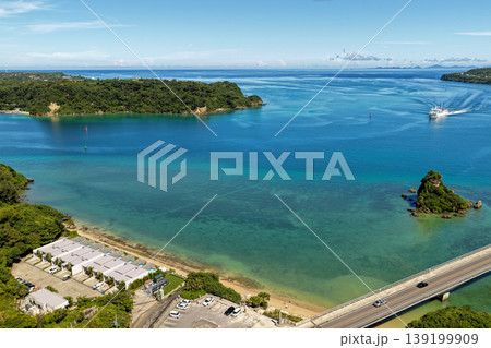 古宇利大橋近くの水路を進む船とエメラルドグリーンの海を真夏の空から捉えた写真 古宇利大橋近くの水路を進む船とエメラルドグリーンの海を真夏の空から捉えた写真 139199909