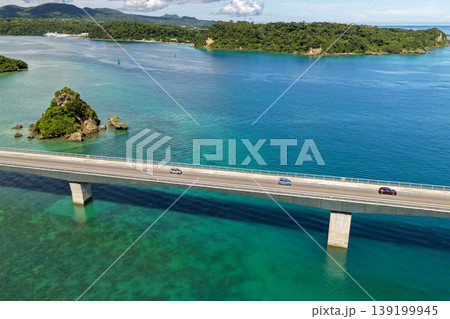 古宇利大橋とエメラルドグリーンの海に浮かぶ小島を真夏の空から捉えた写真 古宇利大橋とエメラルドグリーンの海に浮かぶ小島を真夏の空から捉えた写真 139199945