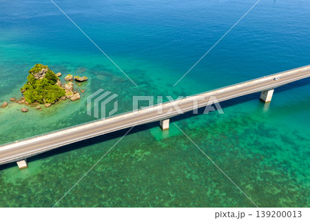 古宇利大橋とエメラルドグリーンの海に浮かぶ小島を真夏の空から捉えた写真 古宇利大橋とエメラルドグリーンの海に浮かぶ小島を真夏の空から捉えた写真 139200013