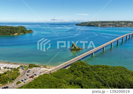 エメラルドブルーの海に伸びる古宇利大橋と古宇利島を真夏の空から捉えた写真 139200019