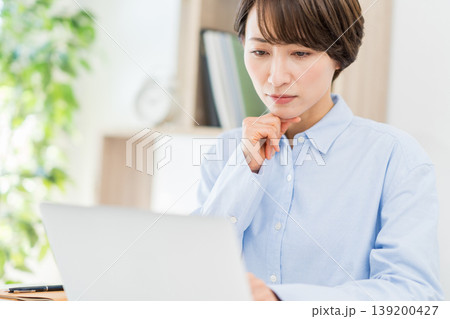 リビングでテレワークをするミドル女性。 リビングでテレワークをするミドル女性。 139200427