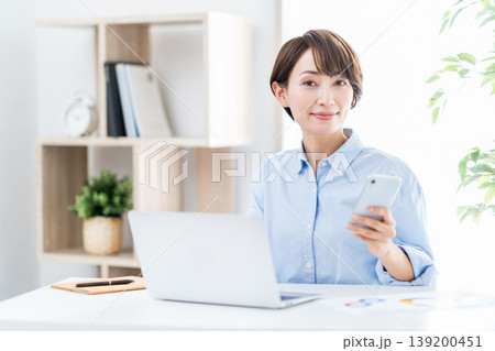 リビングでテレワークをするミドル女性。 リビングでテレワークをするミドル女性。 139200451
