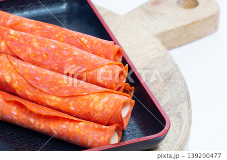 Pepperoni and Parmesan snacks lie on a wooden board. 139200477