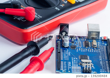Multimeter with measurement probes and electronics board on a white background 139200484