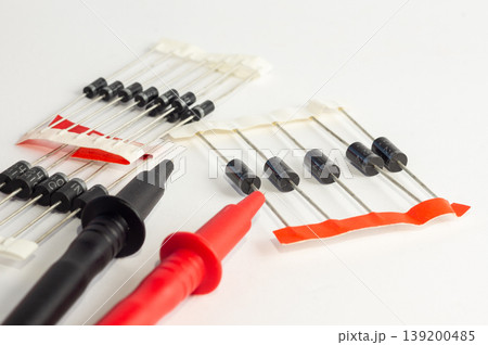 Multimeter with measurement probes and transistors on a white background 139200485