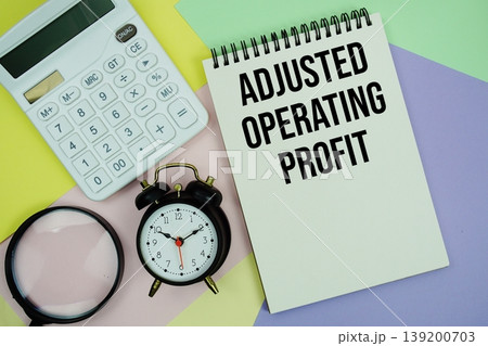 Adjusted Operating Profit text with calculator, alarm clock and magnifying glass 139200703