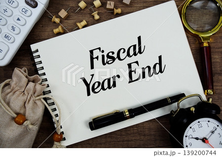 Fiscal Year End text written on notepad with pen, alarm clock, magnifying glass and calculator on wooden background Fiscal Year End text written on notepad with pen, alarm clock, magnifying glass and calculator on wooden background 139200744