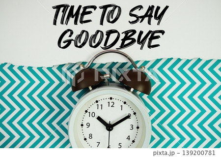 Time To Say Goodbye text written on paper rip with alarm clock flat lay on turquoise chevron background 139200781