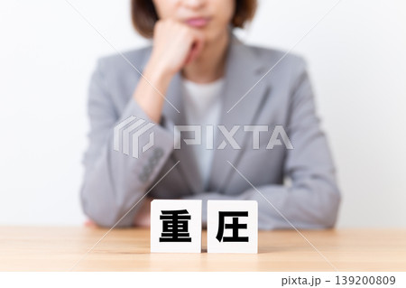 重圧のブロックと悩むスーツ姿のミドル女性 139200809
