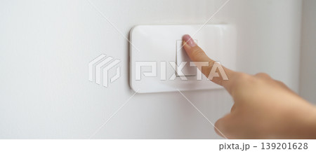 Female finger pushing for turn on light switch on white wall at home room. Woman hand turn off lighting Switch. Energy Saving, energy power control, electrical, eco environment, and lifestyle concept 139201628