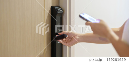 Hand using smartphone for close or Open digital door lock at home or apartment. NFC Technology, Fingerprint scan, keycard, PIN number, smartphone, electrical and contactless lifestyle concepts 139201629