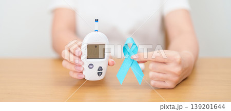 Hand show Blue Ribbon and digital blood glucose meter with lancet pen. high blood sugar level, November World Diabetes Day, Awareness month, Glycemia,, Hyperglycemia and insulin testing and checking 139201644