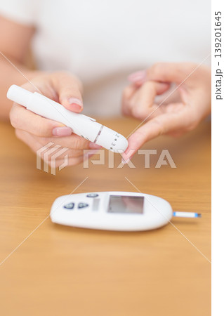 Hand using lancet pen on finger with Blood drop glucose testing or Diabetes checking by digital blood glucose meter. blood sugar level, Diabetes Day, Glycemia, Hypoglycemia, Hyperglycemia and insulin Hand using lancet pen on finger with Blood drop glucose testing or Diabetes checking by digital blood glucose meter. blood sugar level, Diabetes Day, Glycemia, Hypoglycemia, Hyperglycemia and insulin 139201645