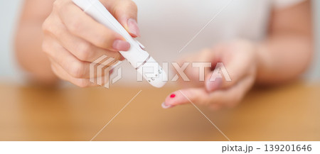 Hand using lancet pen on finger with Blood drop glucose testing or Diabetes checking by digital blood glucose meter. blood sugar level, Diabetes Day, Glycemia, Hypoglycemia, Hyperglycemia and insulin Hand using lancet pen on finger with Blood drop glucose testing or Diabetes checking by digital blood glucose meter. blood sugar level, Diabetes Day, Glycemia, Hypoglycemia, Hyperglycemia and insulin 139201646