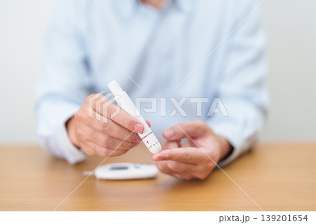 Hand using lancet pen on finger with Blood drop glucose testing or Diabetes checking by digital blood glucose meter. blood sugar level, Diabetes Day, Glycemia, Hypoglycemia, Hyperglycemia and insulin 139201654
