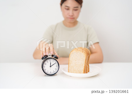 hungry woman with whole wheat bread and clock. concept of intermittent fasting, IF, meal, Time to eat, choosing healthy carbohydrates, balanced diet and weight loss management, Nutrition schedule 139201661