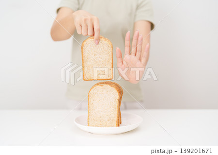 Unhappy woman showing Rejecting gesture and refusing to eat bread. concept of gluten intolerance, gluten sensitivity, carb loading concerns, or a disliking for unhealthy dietary habits Unhappy woman showing Rejecting gesture and refusing to eat bread. concept of gluten intolerance, gluten sensitivity, carb loading concerns, or a disliking for unhealthy dietary habits 139201671