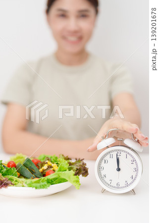 happy smiling woman with fresh organic vegetables plate and alarm clock. intermittent fasting, IF, meal time, nutrition, weight loss, clean eating, Healthy food eating, Wellness, dieting and lifestyle happy smiling woman with fresh organic vegetables plate and alarm clock. intermittent fasting, IF, meal time, nutrition, weight loss, clean eating, Healthy food eating, Wellness, dieting and lifestyle 139201678