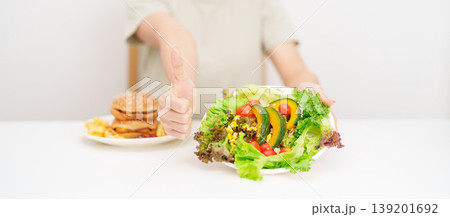 happy woman choose vegetables Salad and thumbs up gesture. Healthy and Unhealthy Food Choice, Calories and Nutrition of vegetables and Hamburger. dieting, weight loss control, junk food and lifestyle happy woman choose vegetables Salad and thumbs up gesture. Healthy and Unhealthy Food Choice, Calories and Nutrition of vegetables and Hamburger. dieting, weight loss control, junk food and lifestyle 139201692