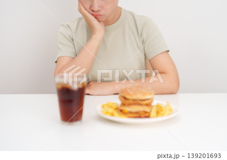Unhappy woman disgust gesture and Bored to eat Juicy beef burger, potato chips and carbonated Soft drinks. Unhealthy, High calorie, Fast food craving, Obesity, diet, weight loss and junk food 139201693
