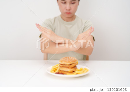 Unhappy woman showing Rejecting and refusing with Juicy beef burger, potato chips and carbonated Soft drinks. Unhealthy, High calorie, Fast food craving, Obesity, diet, weight loss and junk food 139201698