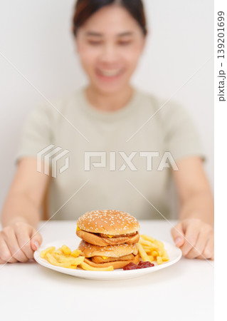 happy woman eating Juicy beef burger with melted cheddar cheese, potato chips. Unhealthy, High calorie, Fast food craving, Obesity, diet, weight loss, junk food and lifestyle 139201699