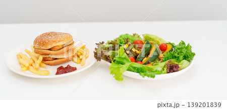 Healthy and Unhealthy Food Choice. Comparison of Calories and Nutrition of vegetables Salad plate and Hamburger. Concept for diet planning, weight loss management, junk food and habit lifestyle Healthy and Unhealthy Food Choice. Comparison of Calories and Nutrition of vegetables Salad plate and Hamburger. Concept for diet planning, weight loss management, junk food and habit lifestyle 139201839