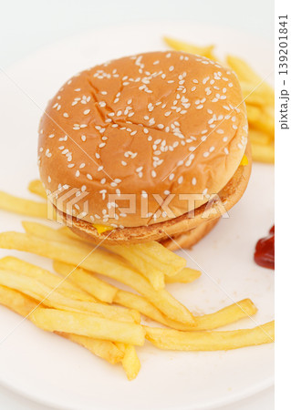 juicy beef burger with melted cheddar cheese, potato chips on table. Unhealthy, High calorie, Fast food craving, Obesity, diet, weight loss, junk food and lifestyle juicy beef burger with melted cheddar cheese, potato chips on table. Unhealthy, High calorie, Fast food craving, Obesity, diet, weight loss, junk food and lifestyle 139201841