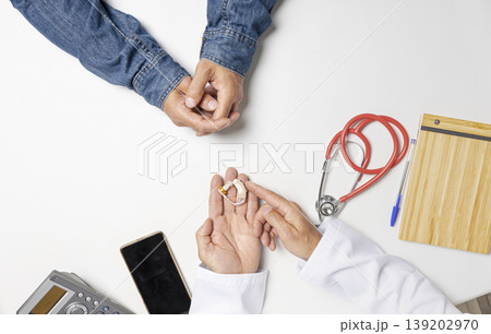 Doctor giving hearing aids to patient on clinic table. Doctor giving hearing aids to patient on clinic table. 139202970