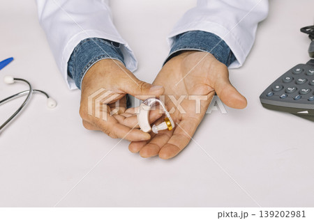 Close up of an Audiologist's hands showing a hearing aid in the hospital clinic. Audiology concept. 139202981