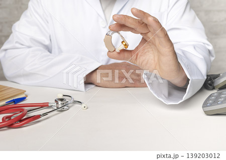 Orthodontic doctor showing hearing aid device for deaf patient 139203012