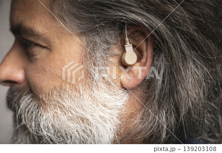 Hearing aid in the ear of a middle-aged man 139203108