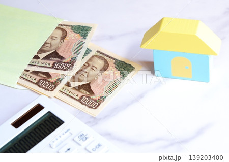 家と一万円札、電卓で、あこがれのマイホームを購入するために資金計画を立てているイメージ 家と一万円札、電卓で、あこがれのマイホームを購入するために資金計画を立てているイメージ 139203400