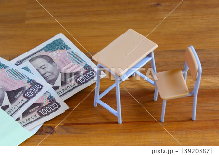 高騰する教育費 - 学校の机と椅子、お金がイメージする、高騰する教育費のイメージ 高騰する教育費 - 学校の机と椅子、お金がイメージする、高騰する教育費のイメージ 139203871