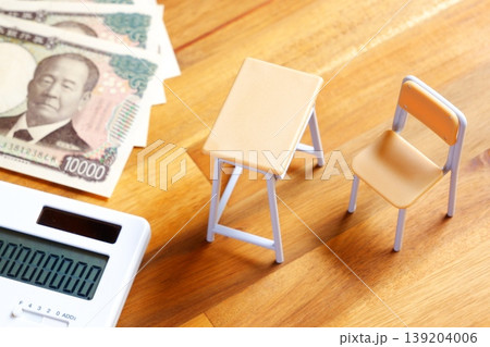 高騰する教育費 - 学校の机と椅子、電卓がイメージする、高騰を続けて家計を圧迫する教育費のイメージ 139204006