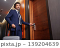 Confident Business Man Entering Hotel Room Using Key Card And Carrying Luggage 139204639