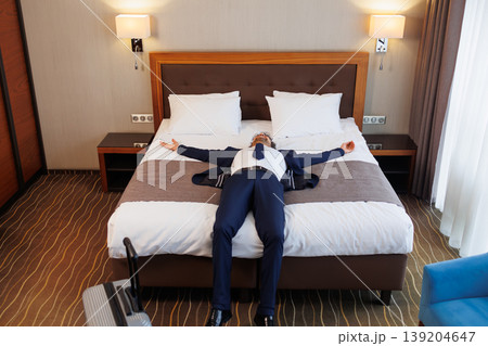 Business traveler lying on hotel bed relaxing after successful trip and long journey 139204647