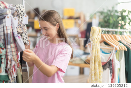 Teen reading labels on scarves in store 139205212