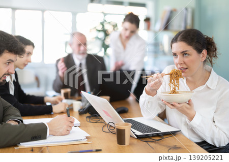 Woman office worker eats noodles while other employees are unhappy with her behavior Woman office worker eats noodles while other employees are unhappy with her behavior 139205221