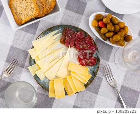 Snack plate - slicing several varieties of cheese, smoked sausage butifarra Snack plate - slicing several varieties of cheese, smoked sausage butifarra 139205223