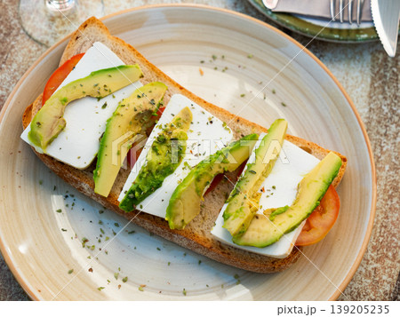 Open-faced sandwich with tomato, avocado, and cheese 139205235